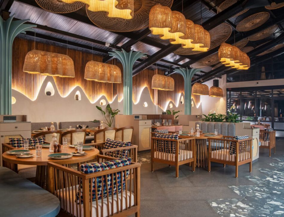 Anjuna restaurant — rattan pendants, cove-lit wall